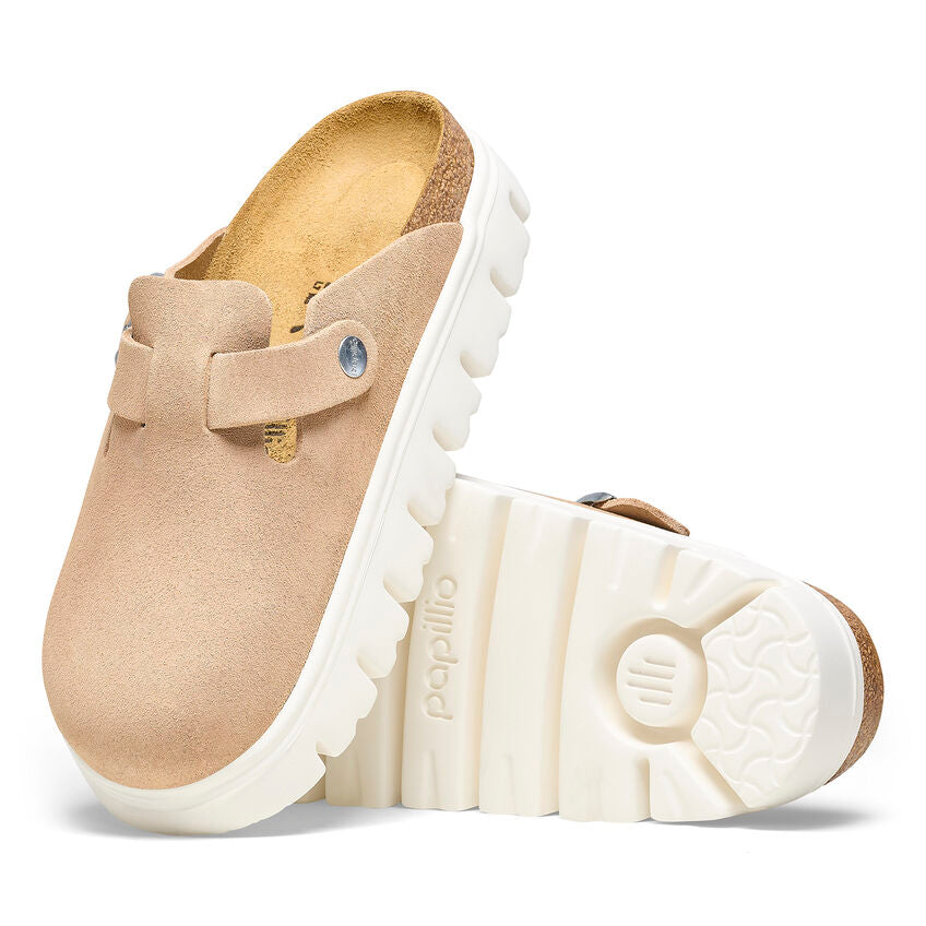 Beige suede Birkenstock Boston clogs with a chunky white platform sole and cork footbed on a white background.