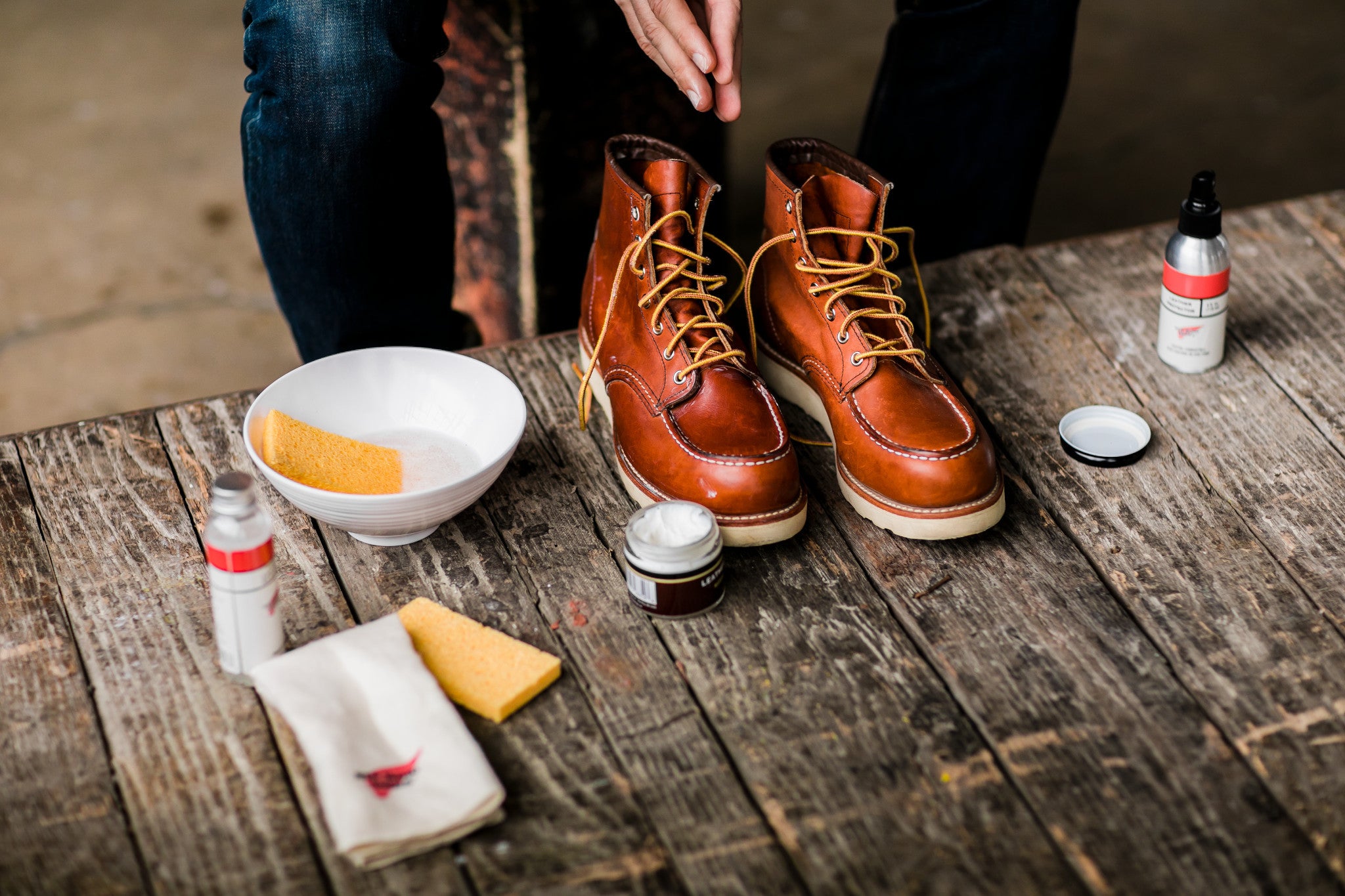 A man is brushing his boots, actively caring for them to keep them clean and in good condition.