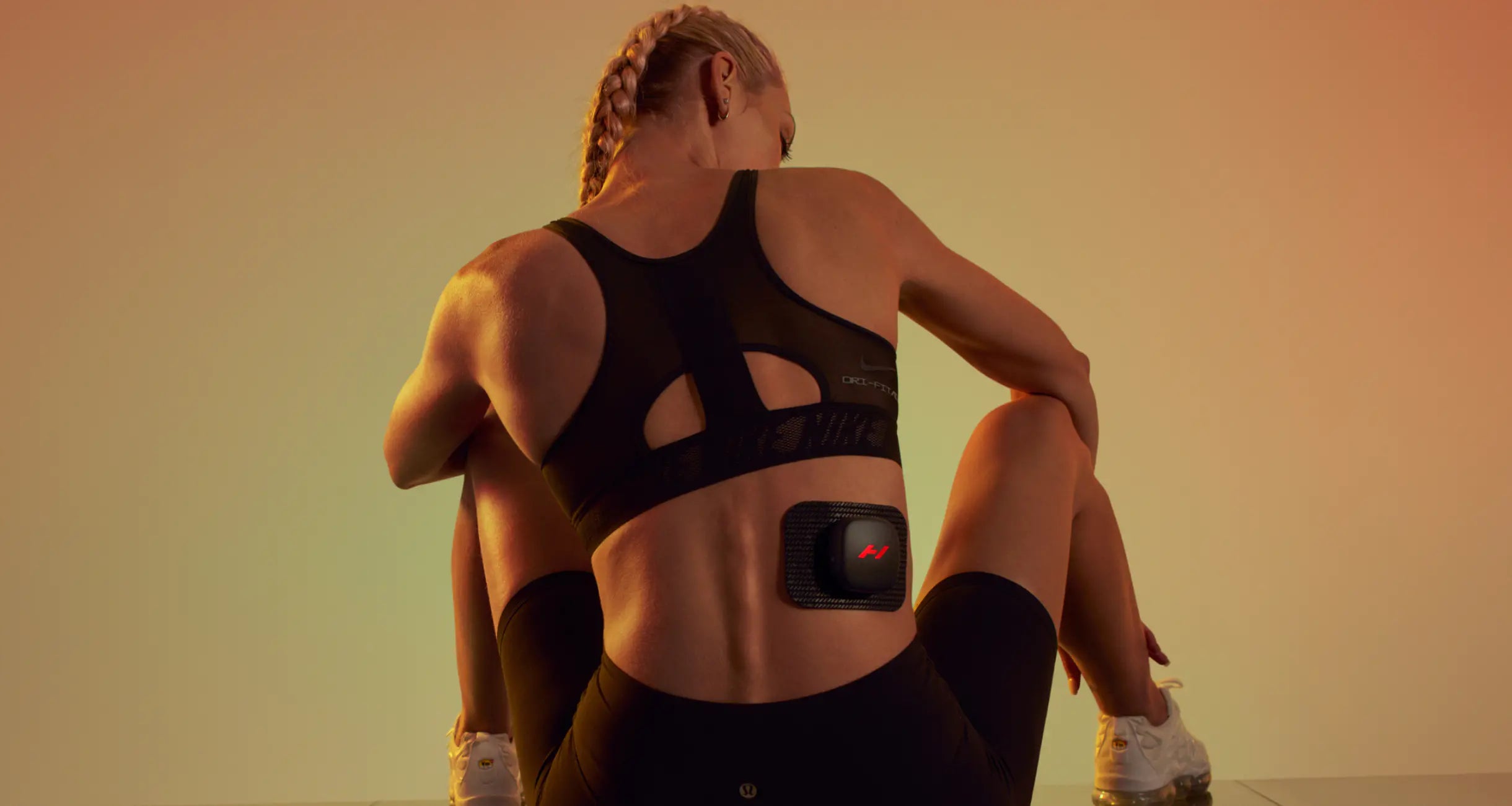 A woman in athletic clothing sits on the floor, her back to the camera, evoking a sense of solitude and reflection-Hyperrice-Footprint USA