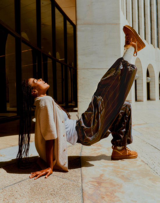 A woman in a white shirt and brown pants performs a handstand,
showcasing her skill and the shoes she is wearing.