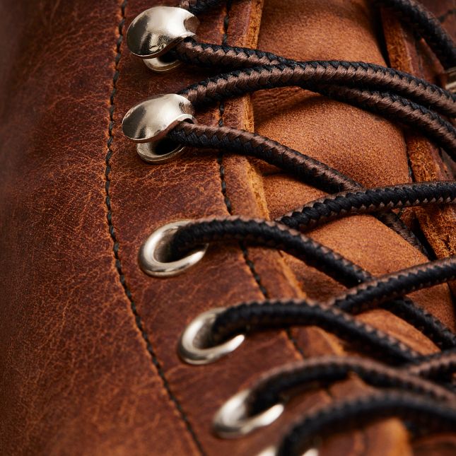 Close-up of Red Wing Iron Ranger boot in copper leather with brass speed hooks and durable black and brown laces.